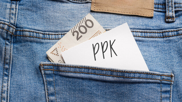  White card with a handwritten inscription "PPK", put into the pocket of blue pants jeasnow, next to Polish banknotes PLN (selective focus)