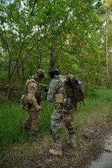 Soldiers in camouflage install a trip wire in the forest