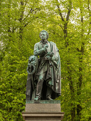 bronze staue of the writer Esaias Tegnér against a green foliage at Lundagård