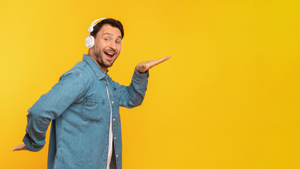 A smiling man wearing headphones and a denim jacket stands against a vibrant yellow backdrop,...