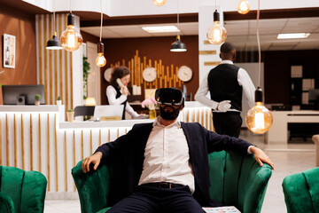 Businessman works with vr headset in hotel lobby, using new 3d interactive vision glasses before...