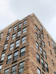 tall apartment building detail with colorful bricks, windows reflecting cloudy sky (housing real estate flats new jersey waterfront)