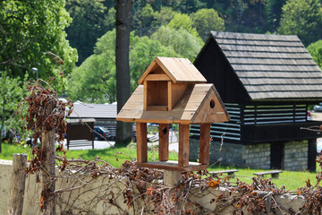 A wooden bird feeder that looks like a house