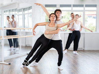 Young guy and adult woman dancers rehearsing pair ballet in studio