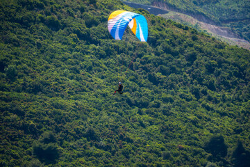 Paraglider flying over mountains in summer day