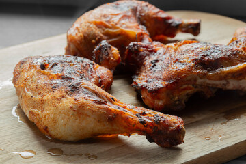 Piri Piri chicken, Coated in a hot spicy marinade, resting after being cooked. On a wooden chopping board in a kitchen.