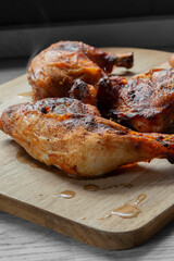 Piri Piri chicken, Coated in a hot spicy marinade, resting after being cooked. On a wooden chopping board in a kitchen.