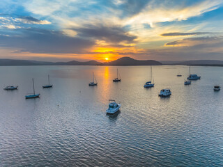 Hazy aerial sunrise waterscape in soft pastel colours with boats and high cloud
