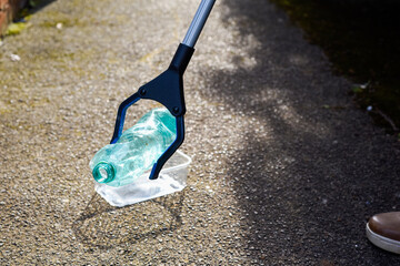 Picking up plastic waste and rubbish which has been dropped on the pavement to clean up and care for the environment