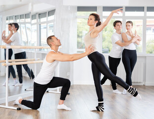 Young man and adult woman dancers rehearsing pair ballet in studio
