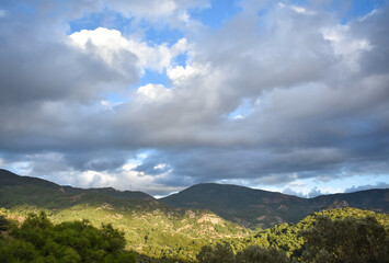 Fototapeta na wymiar Green mountain scene with white clouds and blue sky 