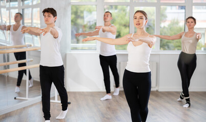 Group of men and women rehearsing ballet moves in dance studio