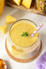 Pineapple turmeric smoothie with fresh mint in a glass on white table. Top view, close-up. Healthy...