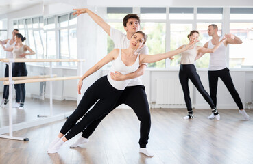 Young guy and young woman perform paired ballet dance in studio