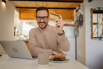 Adult caucasian man have breakfast and shopping online at kitchen