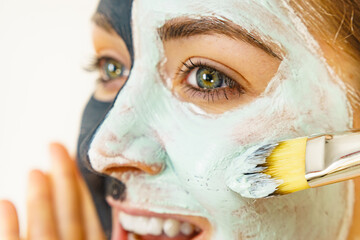 Female applying green mud facial mask