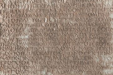 Vintage text background. Close-up of an ancient Greek stone inscription with weathered characters...