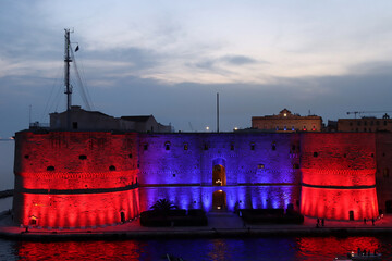 Aragonese Castle colored with red and blue lights, colors of the city of Taranto. Puglia, Italy