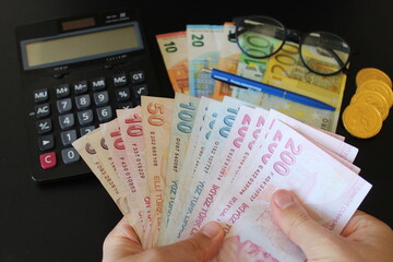The paper currency of Turkey. Calculator in the background.Turkish lira banknotes. man counting...