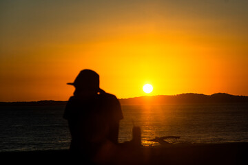 Silhouette of an unidentified person enjoying the dramatic sunset at Praia da Barra in the city of...