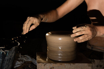 Close-up portrait of artisan's hand shaping ceramic pot. Clay art