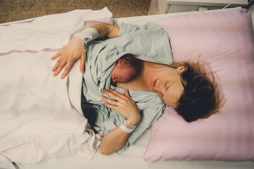 Mother and newborn. Child birth in maternity hospital. Young mom hugging her newborn baby after...