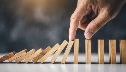 Hand halting wooden dominoes: Symbolic of preventing business crises, risk management, and protective measures against adverse effects