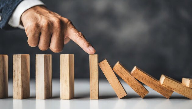 Hand halting wooden dominoes: Symbolic of preventing business crises, risk management, and protective measures against adverse effects