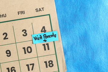 Visiting parents house schedule concept. Written reminder note on calendar.