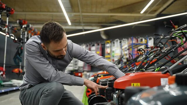 A man in garden center of hardware store chooses lawn mower