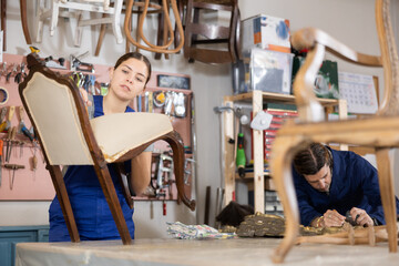 Process of restoring an old chair - female restorer carefully removes the chair upholstery