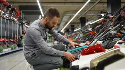 Gardener in garden store choosing lawnmower