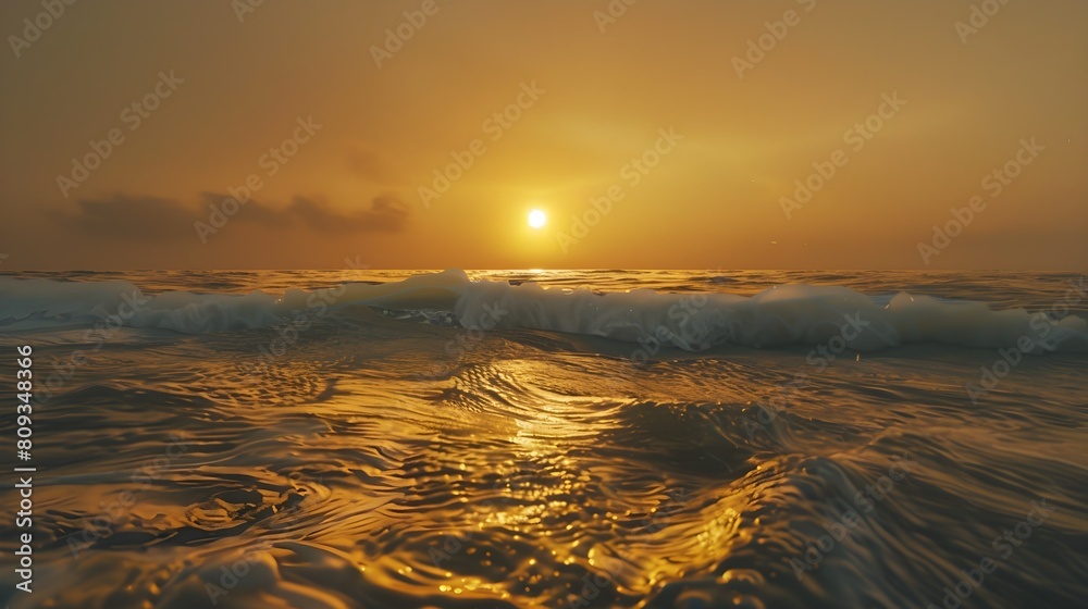 Wall mural the golden sun sinks below the horizon, casting a warm glow over the ocean waves as they roll gently