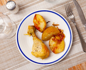 Appetizing roasted chicken leg served with skinned baked potatoes. Tasty homemade dinner..