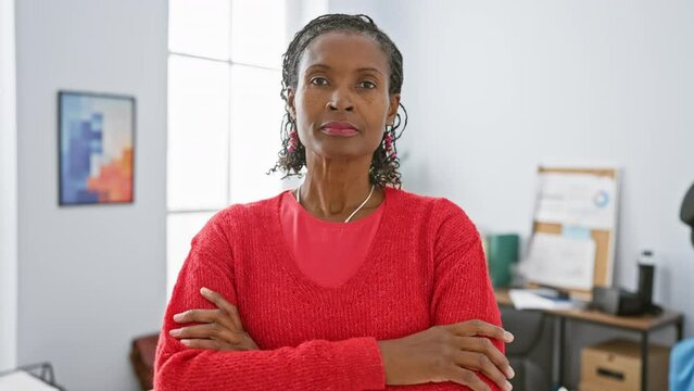 Confident african american woman with crossed arms standing in a modern office setting