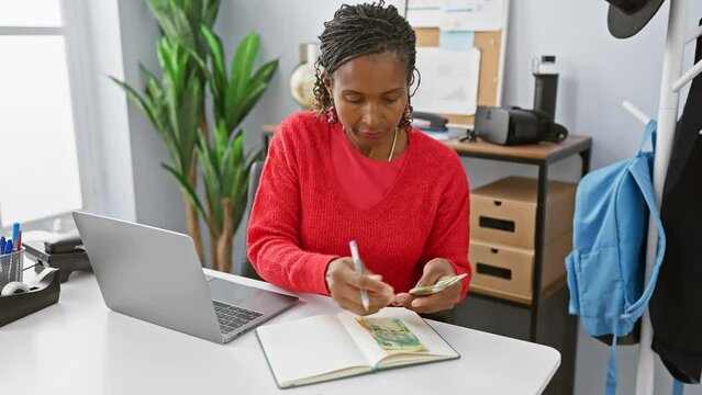African woman budgeting with south african rand in a modern office setting