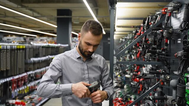 A man in a hardware store chooses a new screwdriver or drill
