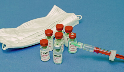 Covid-19 vaccine glass vials and full plastic syringe with sharp needle