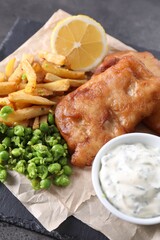 Tasty fish, chips, sauce and peas on grey table, closeup