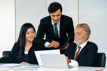 Senior caucasian manager working in office with assistance of young Asian business people and...