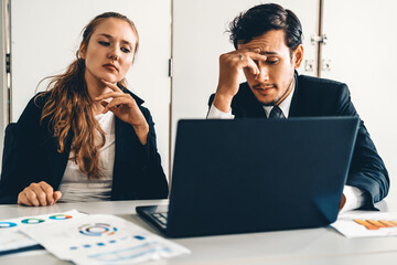 Unhappy serious businessman and businesswoman working using laptop computer on the office desk. Bad...