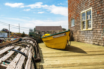 working  boat: traditional small wooden fishing dory sitting on wooden deck outside a port building...