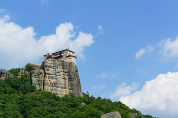 青空のもとメテオラの高台にそびえる奇岩を見上げる風景