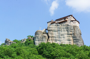 青空のもとメテオラの高台にそびえる奇岩を見上げる風景
