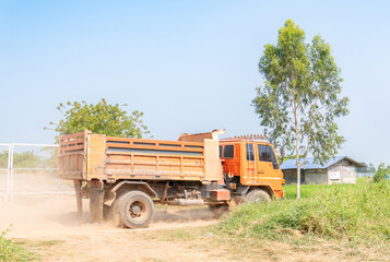 Dump truck carrying soil moving on road.