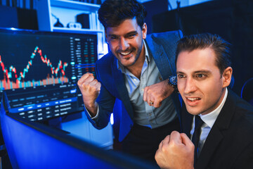 Successful two stock exchange traders raising fist up for digital currency achievement focusing on...