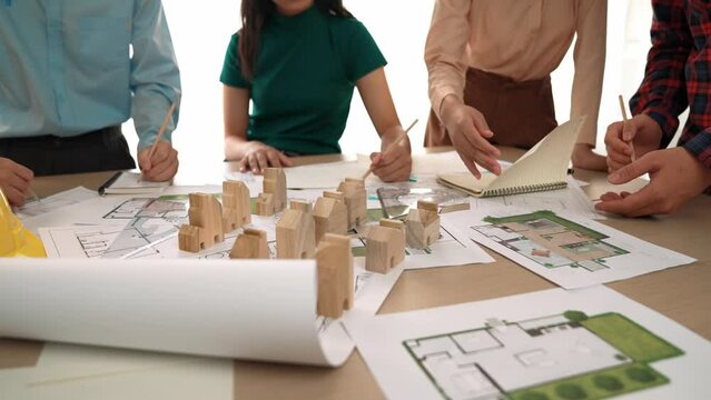 Smart architect and safety engineer discussion about building blueprint on table with architectural document, measurement tools and wooden block scatter around at modern office. Closeup. Delineation.