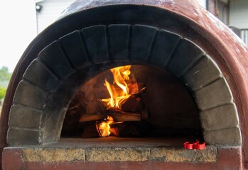 Lit fire in a pizza oven preparing to make pizzas for lunch
