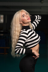 Portrait of a young beautiful blonde girl in a sports uniform in the gym.