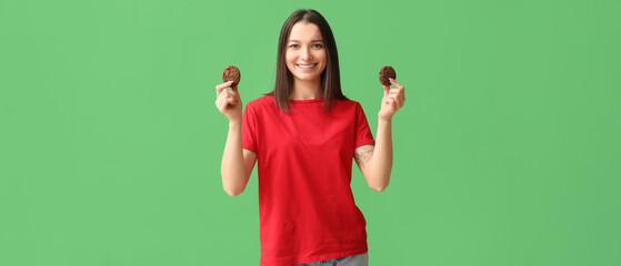 Beautiful young woman with tasty cookies on green background